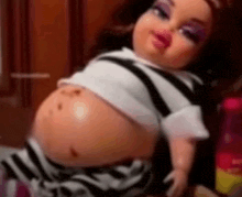 a doll with a very large belly is wearing a striped shirt and striped shorts .