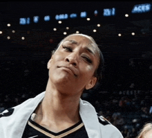 a female basketball player stands in front of a screen that says aces