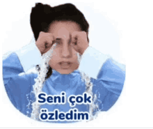 a woman in a blue shirt is crying with water pouring out of her eyes and the words seni çok ozledim on the bottom