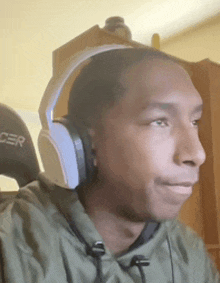 a man wearing headphones and a green hoodie is looking at the camera .