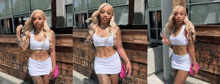 a woman in a white crop top and white skirt is standing in front of a building .