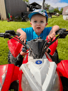 a little boy wearing a blue hat is sitting on a red polaris atv