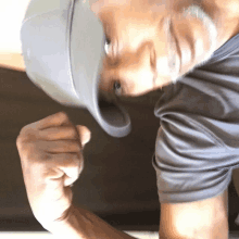 a man wearing a hat and a gray shirt is flexing his arm