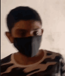 a young boy wearing a black mask and glasses is looking at the camera .