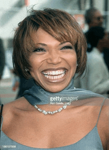 a woman wearing a necklace and a scarf is smiling for the camera