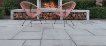 two pink chairs are sitting in front of a fire place