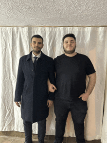 two men standing in front of a white curtain