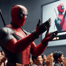 a man in a deadpool costume applauds in front of a crowd of people