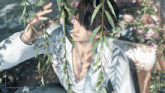a man in a white shirt is surrounded by leaves and a recorder says rec at the bottom