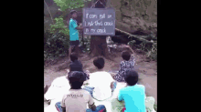 a group of children sit on the ground in front of a sign that says " if cops pull up i put that clock in my crack "