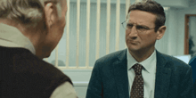 two men in suits and ties are talking to each other