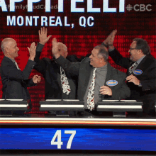 a group of men giving each other a high five in front of a screen that says montreal qc on it