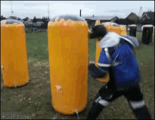 a man in a blue jacket is standing in front of a row of yellow cylinders that are covered in foam