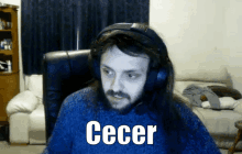 a man wearing headphones and a blue sweater says " cecer " in white letters