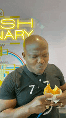 a man is eating a donut in front of a neon sign that says sh january .