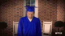 a man in a blue graduation cap and gown is standing in front of a brick wall with netflix written on the bottom