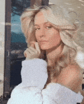 a woman with blonde hair is wearing a white sweater