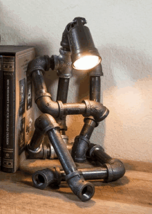 a lamp made out of pipes sits on a table next to a book titled " miss peregrines home for peculiar children "