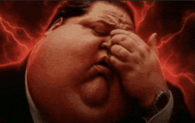 a man with a large belly is covering his eyes with his hands