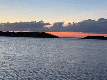 a sunset over a large body of water with a small island in the distance