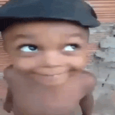 a baby wearing a hat is making a funny face and smiling .