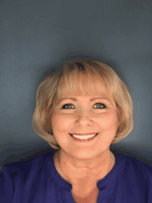 a woman wearing a purple shirt smiles for the camera