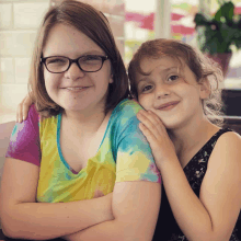 two girls are posing for a picture and one has glasses on