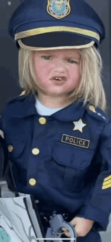 a little girl is dressed in a police officer costume and holding a gun .