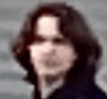 a blurry picture of a man 's face with long dark hair