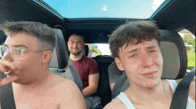 a group of young men are sitting in a car with one of them crying