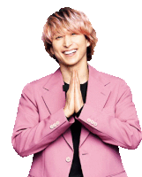 a man wearing a pink jacket is smiling and holding his hands together