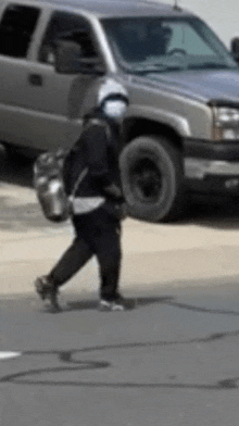 a person is walking down the street with a backpack and a pot on their back .