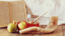 a shofar horn sits on a wooden table next to an apple and a jar of honey