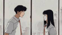 a boy and a girl are standing next to each other in front of a window and looking at each other .