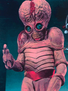 a purple alien with a red belt around his waist giving the middle finger