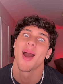 a young man with curly hair is making a funny face with his tongue out .