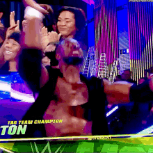 a man is standing in front of a crowd with the words tag team champion ton on the screen