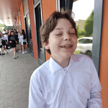 a boy in a white shirt is making a funny face with his eyes closed