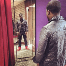 a man standing in front of a mirror wearing a black leather jacket