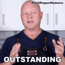 a man wearing an apron says outstanding in front of a white cabinet