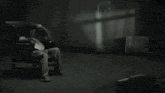 a black and white photo of a person laying on a bed in the dark .