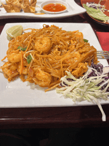 a plate of food with noodles shrimp and cabbage on a table