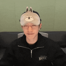 a man wearing a sleep mask and a sweater that says maniac on it