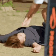 a person is laying on the ground with their feet up and a person is kicking them .