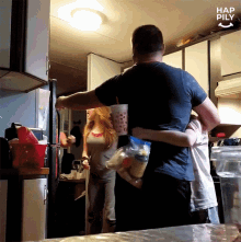 a man in a blue shirt is hugging a woman in a kitchen with the words hap pily written on the ceiling