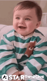 a baby wearing a green and white striped shirt with a teddy bear on it