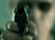 a person is pointing a gun at the camera with a green background .