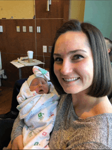 a woman holds a newborn baby in her arms and smiles