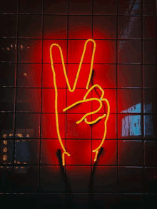 a neon sign of a hand making a peace sign .