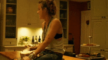 a woman sits at a kitchen counter with a cake on it